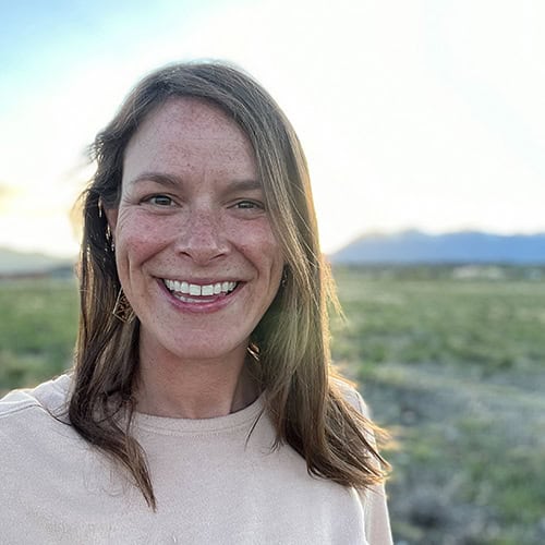 A woman standing in front of a field smiling.